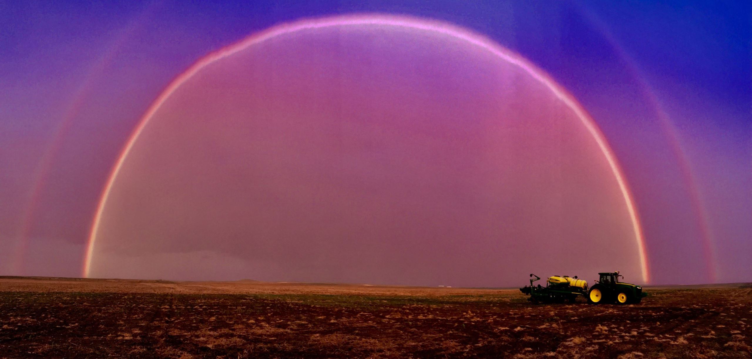 Rainbow over a field with a tractor