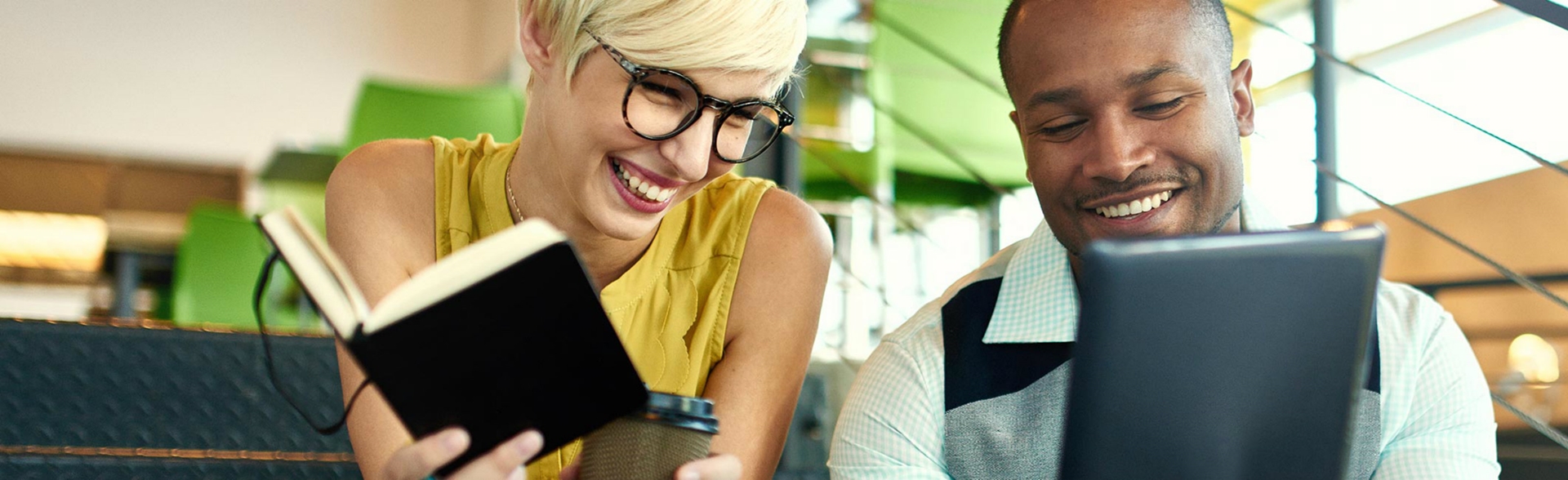 A couple smiling as they look into a tablet