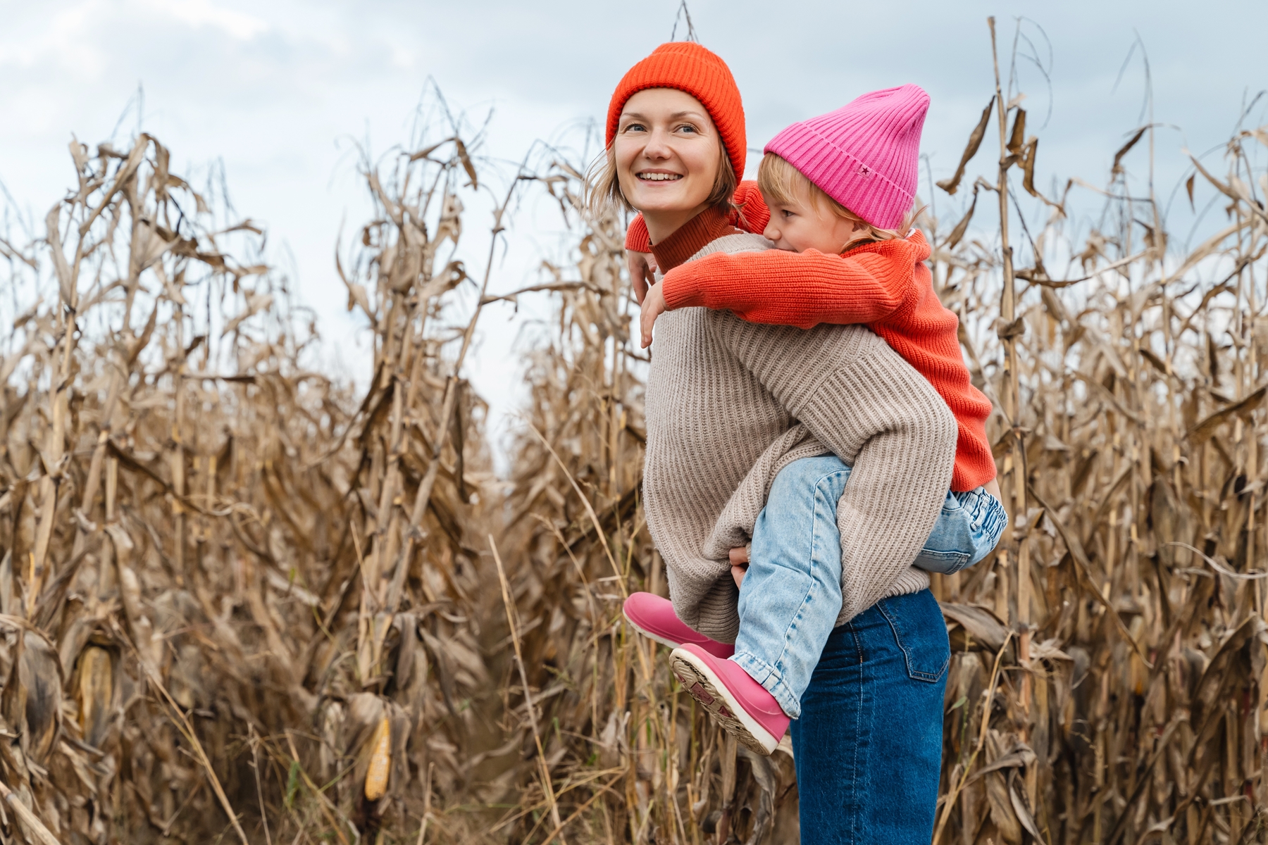 Mother and daughter walking playing together in corn field