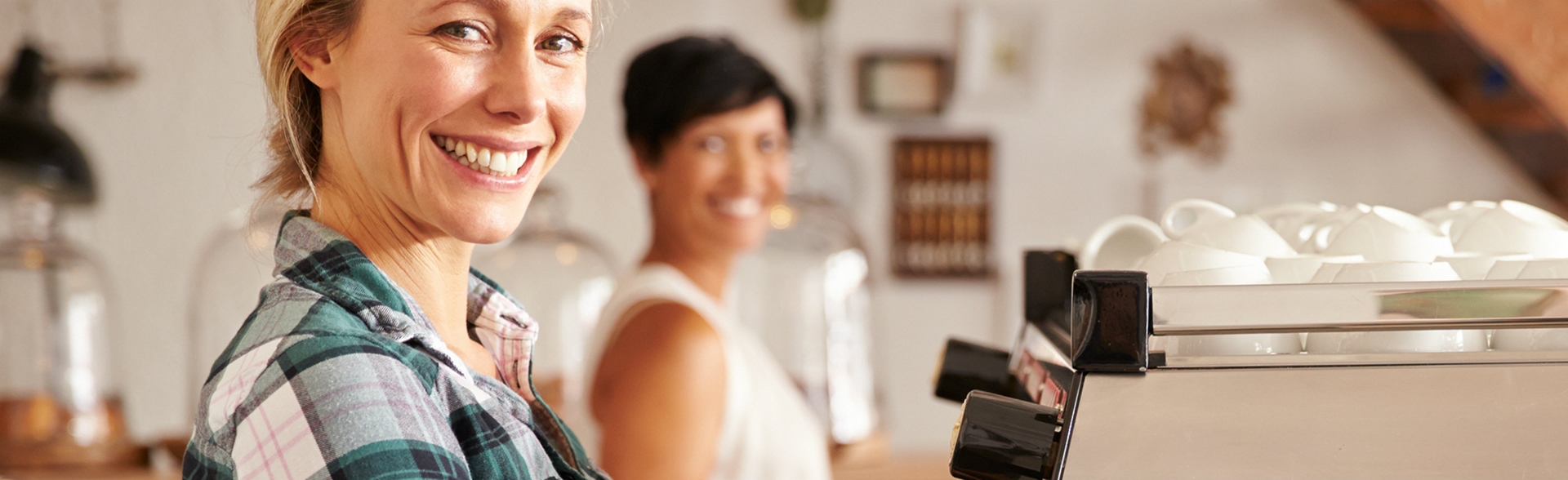 A women smiling in front of a coffee making machine