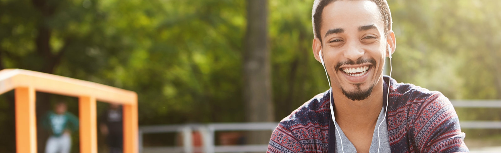 A man outdoors with ear phones smiling